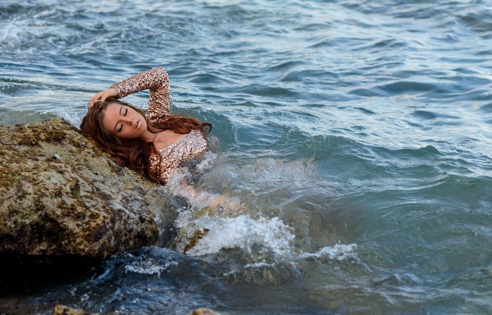 Woman in sequined dress in the ocean waves