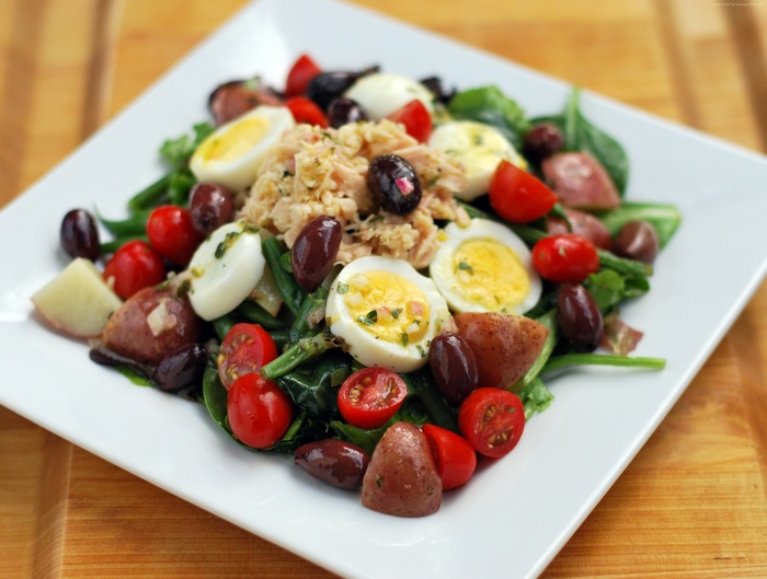 Salad with tuna, eggs, potatoes, tomatoes, olives, and spinach