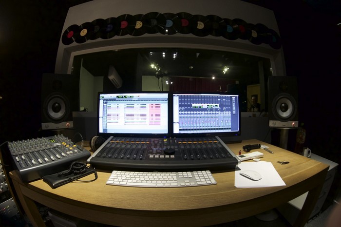 Recording studio with dual monitors, audio mixer, and vinyl records