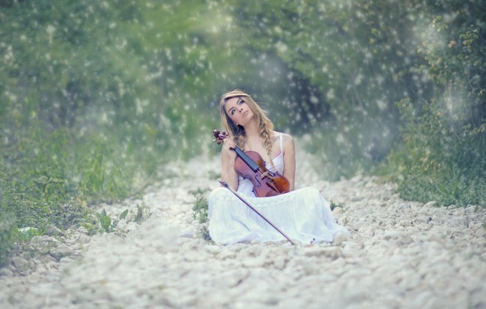Woman in white dress holding a violin outdoors