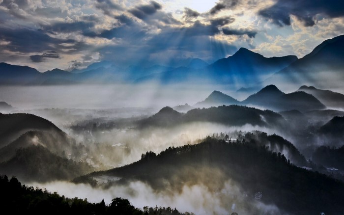 Sun rays over misty mountains at dawn