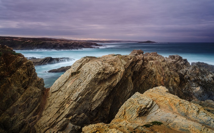 Rocky coastline with ocean waves under a cloudy sky
