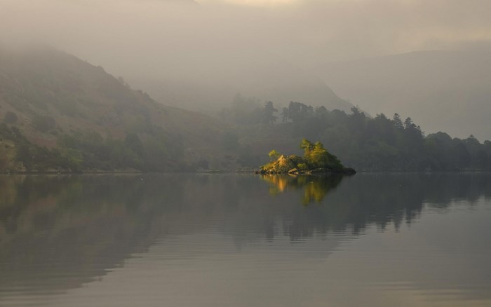 Misty lake with island and reflection at dawn