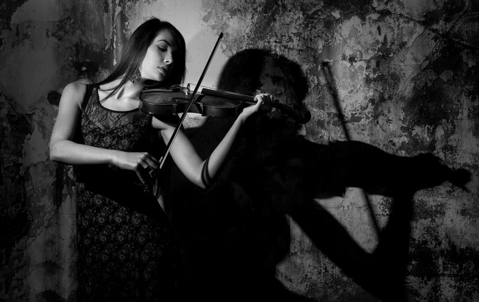 Woman playing violin in a dark room