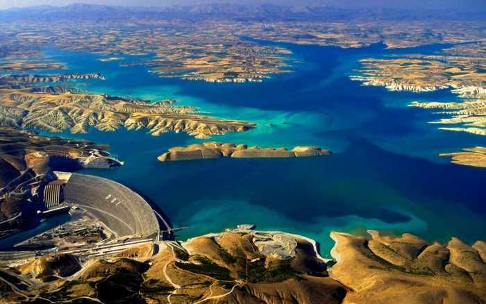Aerial view of a large dam and reservoir in a mountainous landscape