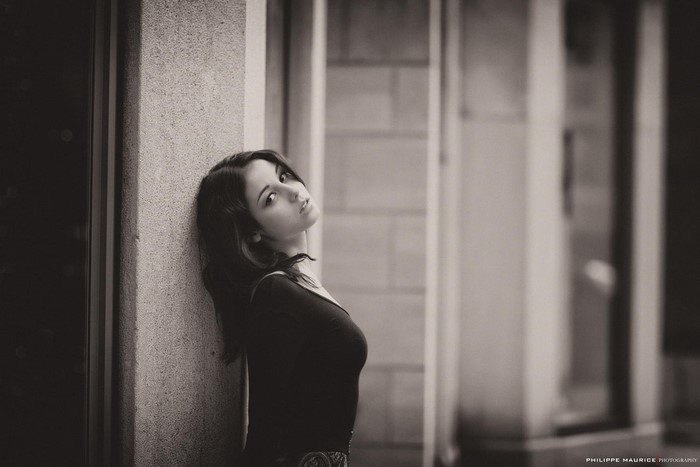 Monochrome portrait of a woman leaning against a wall