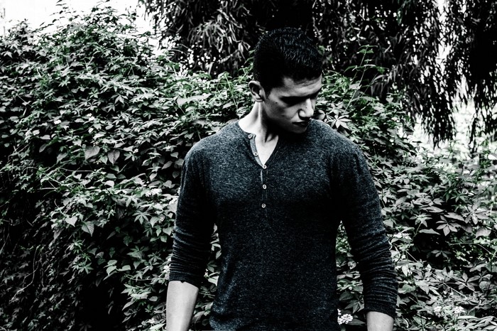 Man in dark shirt standing in front of foliage