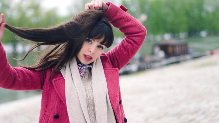 Woman in pink coat with hands in hair