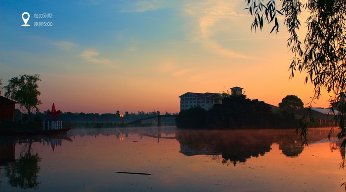 Sunrise over a calm lake with a building and trees