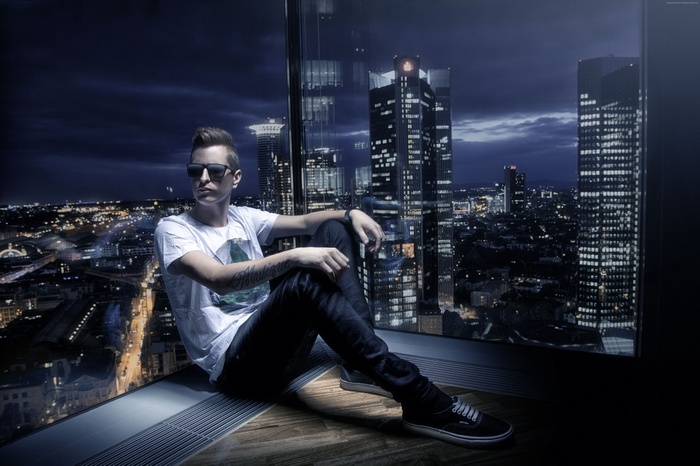 Robin Schulz sitting by a window overlooking a city at night