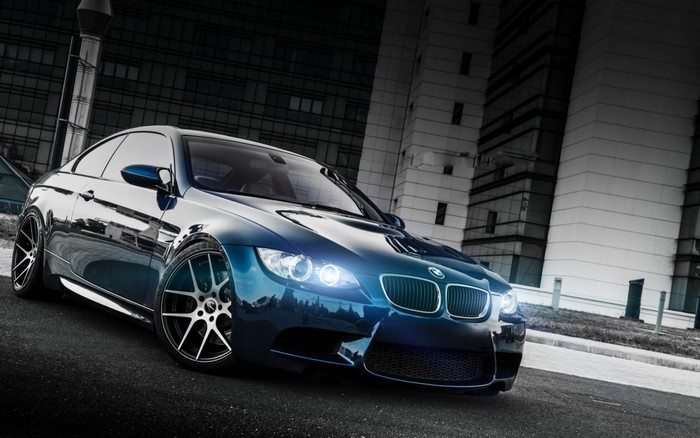 Blue BMW M3 Coupe parked in front of modern buildings