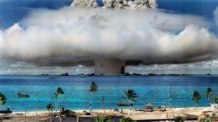 Nuclear explosion over the ocean with ships and beach