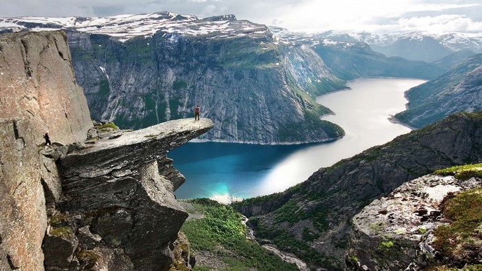 Man standing on Trolltunga rock in Norway overlooking a fjord
