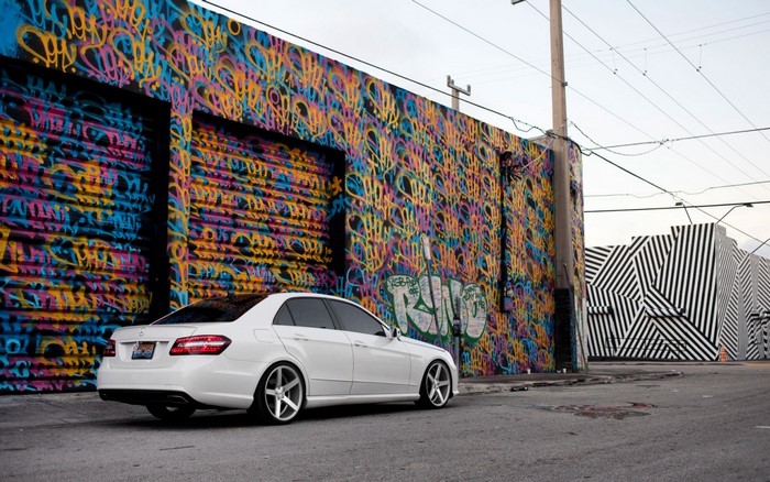 White Mercedes-Benz E-Class parked by graffiti wall