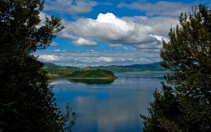 Calm lake with green islands and cloudy sky