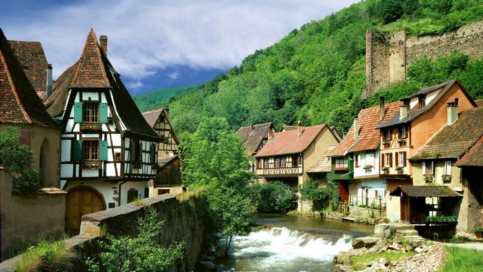 Half-timbered houses along a river in a green valley