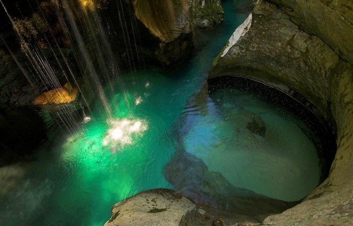 Waterfall cascading into a turquoise canyon pool in Slovenia