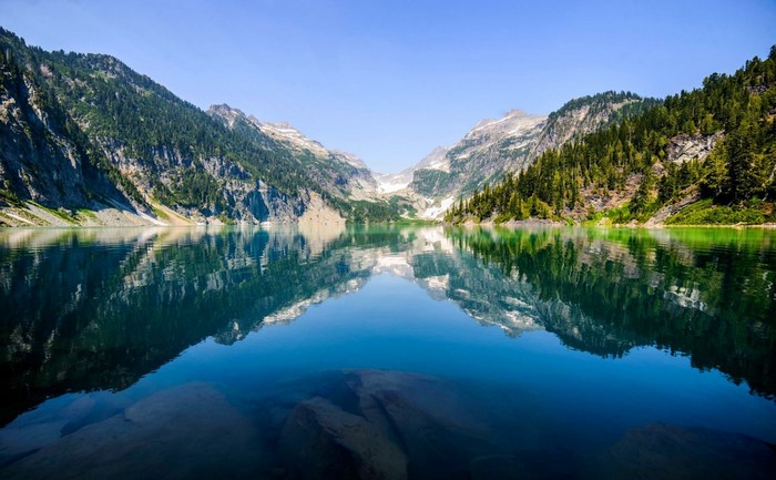 Mountain lake with reflections of mountains and forest