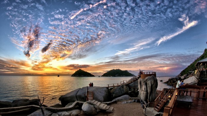 Sunset over the ocean with islands and a wooden deck