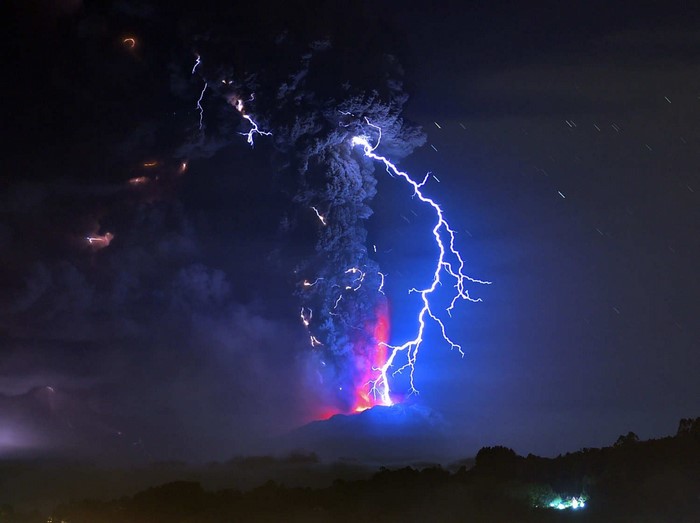 Lightning strikes a volcano erupting at night