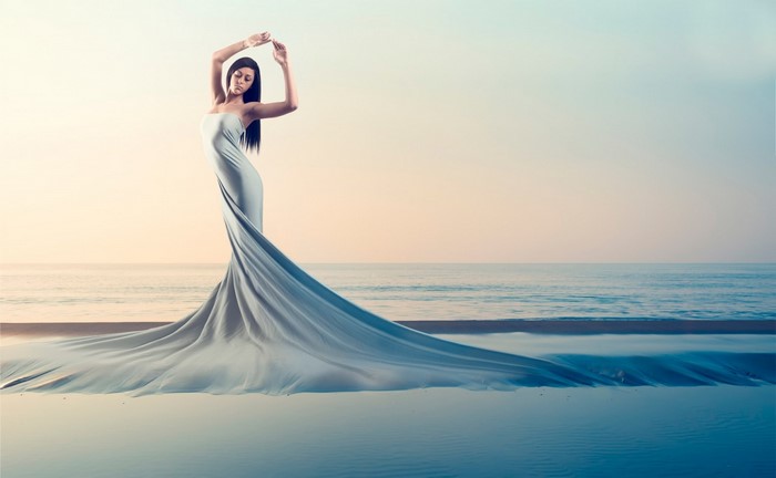 Woman in flowing dress on beach at sunset