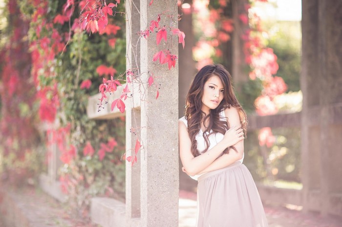 Woman Standing by Blooming Pink Vines in Spring