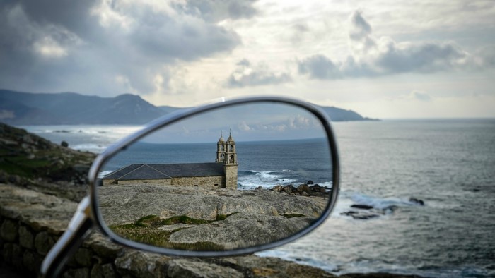 Church reflected in a motorcycle mirror by the sea