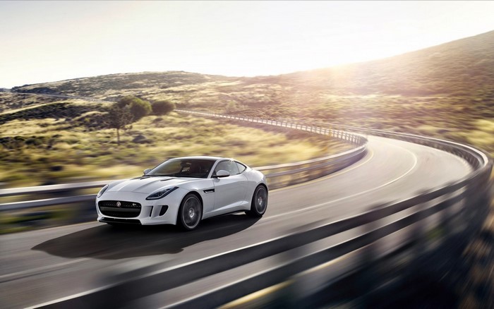 White Jaguar F-Type driving on a winding road