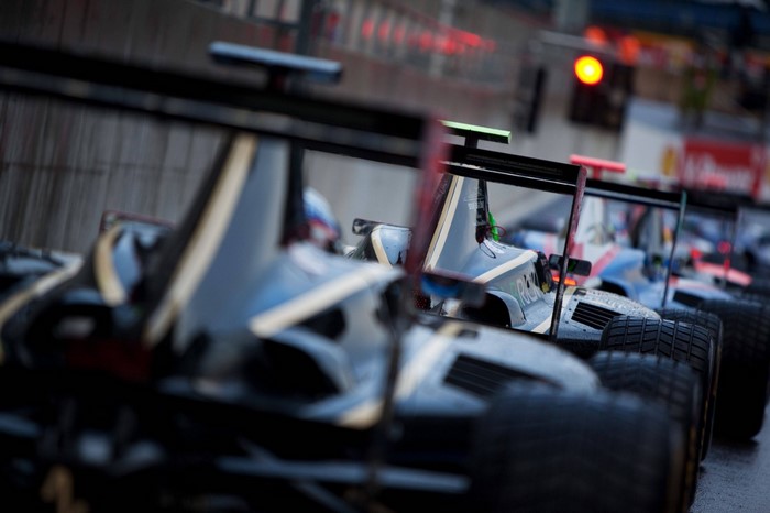 Formula 1 cars lined up on a wet race track