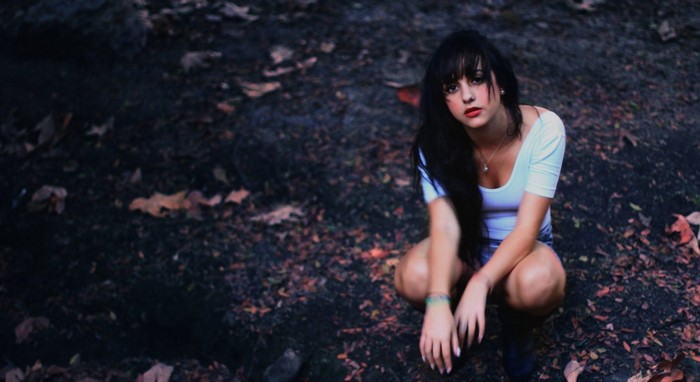 Woman with long dark hair crouching outdoors
