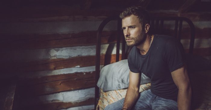 Dierks Bentley sitting on a bed in a log cabin