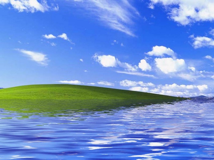 Green hill with blue sky and water reflection