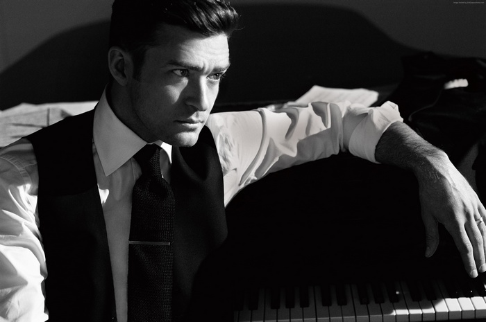 Justin Timberlake in a vest and tie by a piano