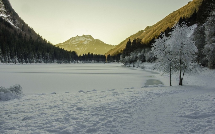 Frozen lake and snow-covered mountains at sunset