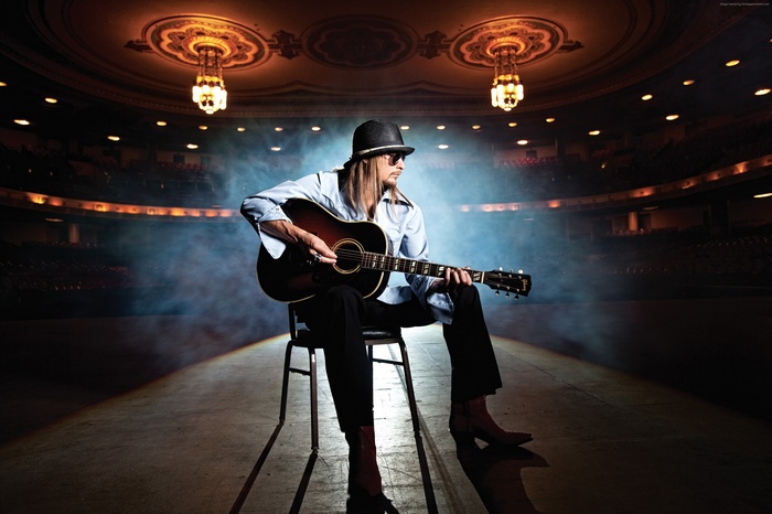 Kid Rock playing guitar on stage in theater