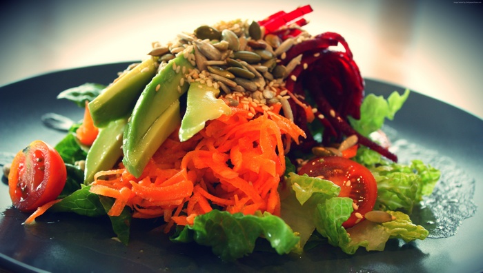 Salad with avocado, carrots, tomatoes, and seeds