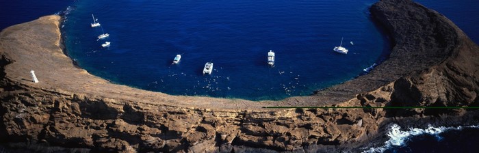 Aerial view of a rocky coastline with boats and a lighthouse