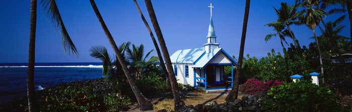 Small white church with blue trim by the ocean