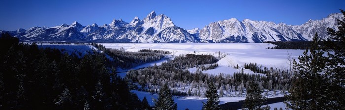 Snowy mountain range panorama with forest and frozen lake