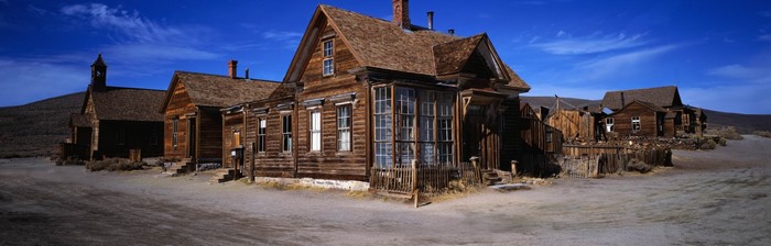 Abandoned wooden buildings in a ghost town under a blue sky