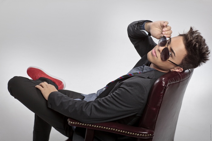 Prince Royce wearing sunglasses in a chair