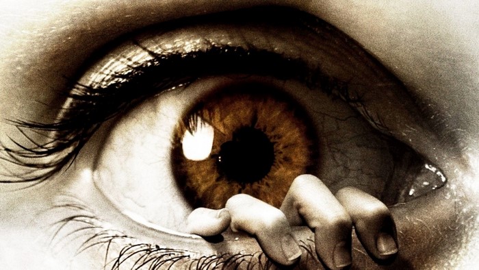 Close-up of a human eye with a hand reaching out