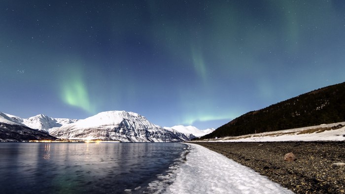 Aurora Borealis over snow-covered mountains and a lake