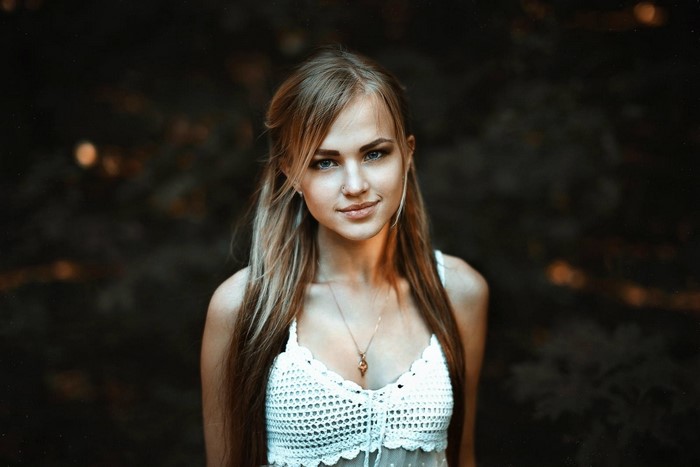 Woman with long blonde hair and blue eyes wearing a white top