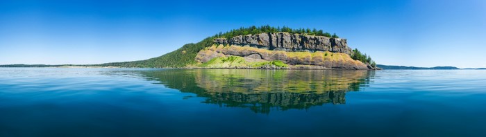 Island cliff with trees reflected in the water