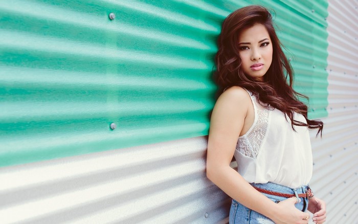 Asian woman leaning against a corrugated metal wall