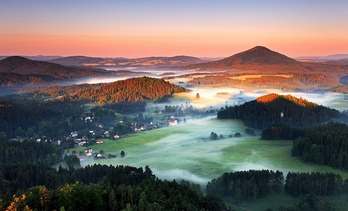 Misty valley with hills and mountains at sunrise