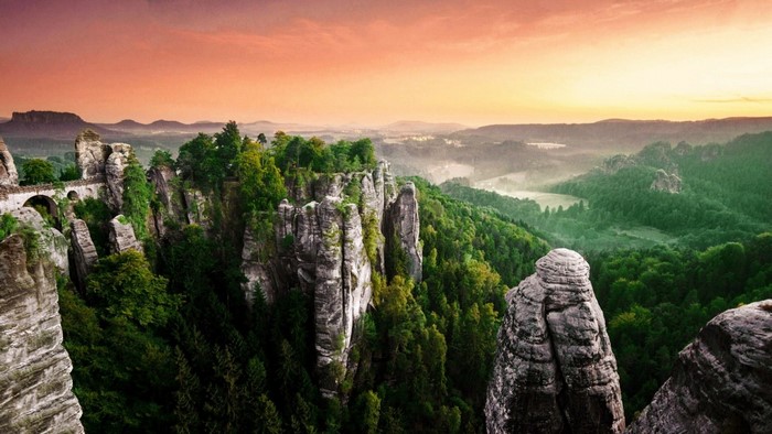 Rocky cliffs and forest valley at sunset