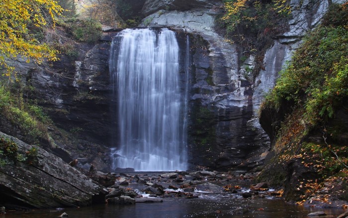 Waterfall cascading over rocky cliff in autumn