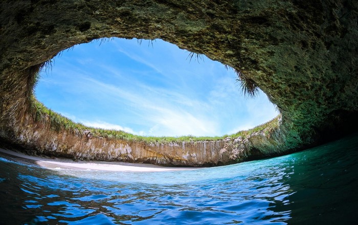 Cave opening overlooking a tropical beach and ocean